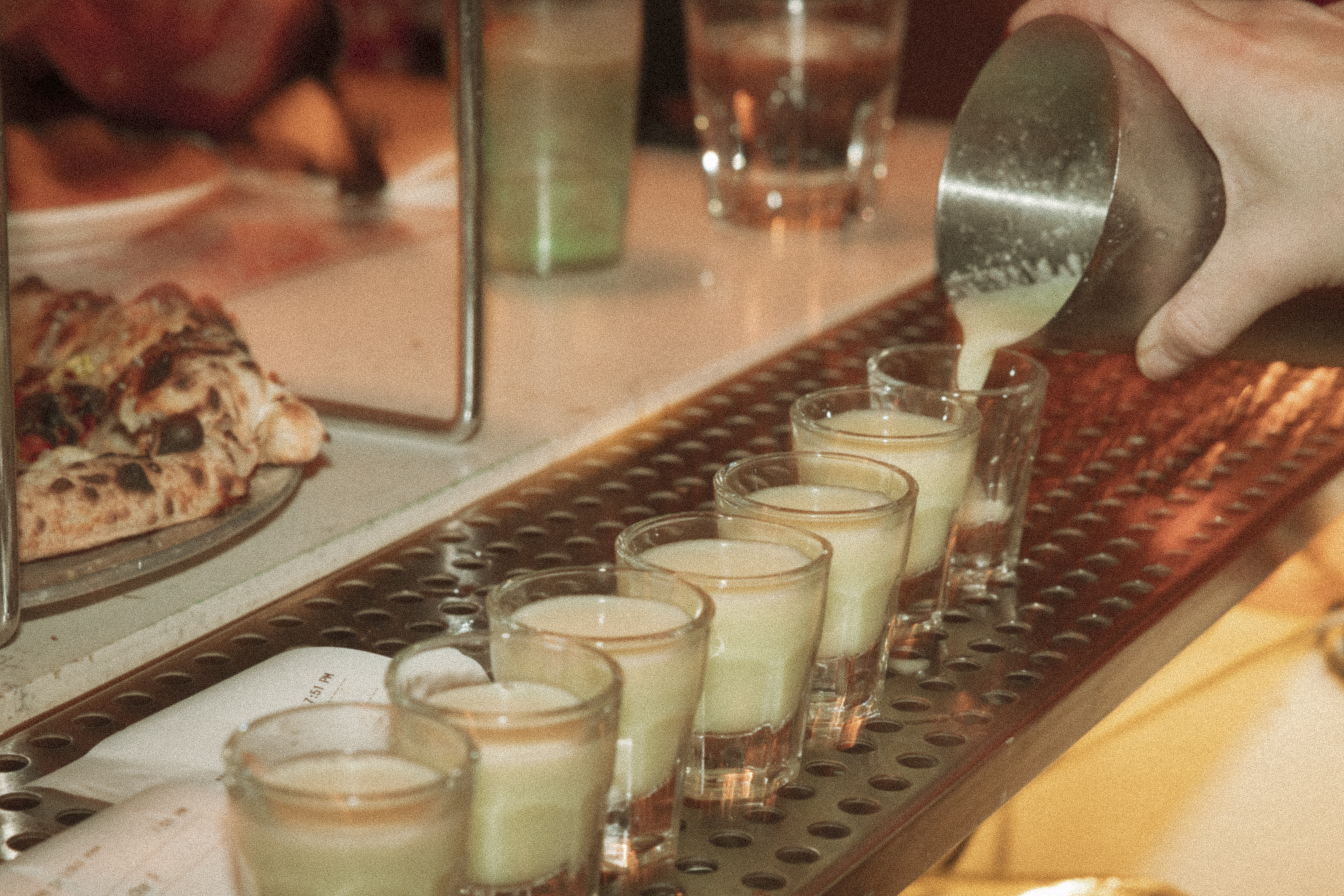 a group of shot glasses being poured into a row