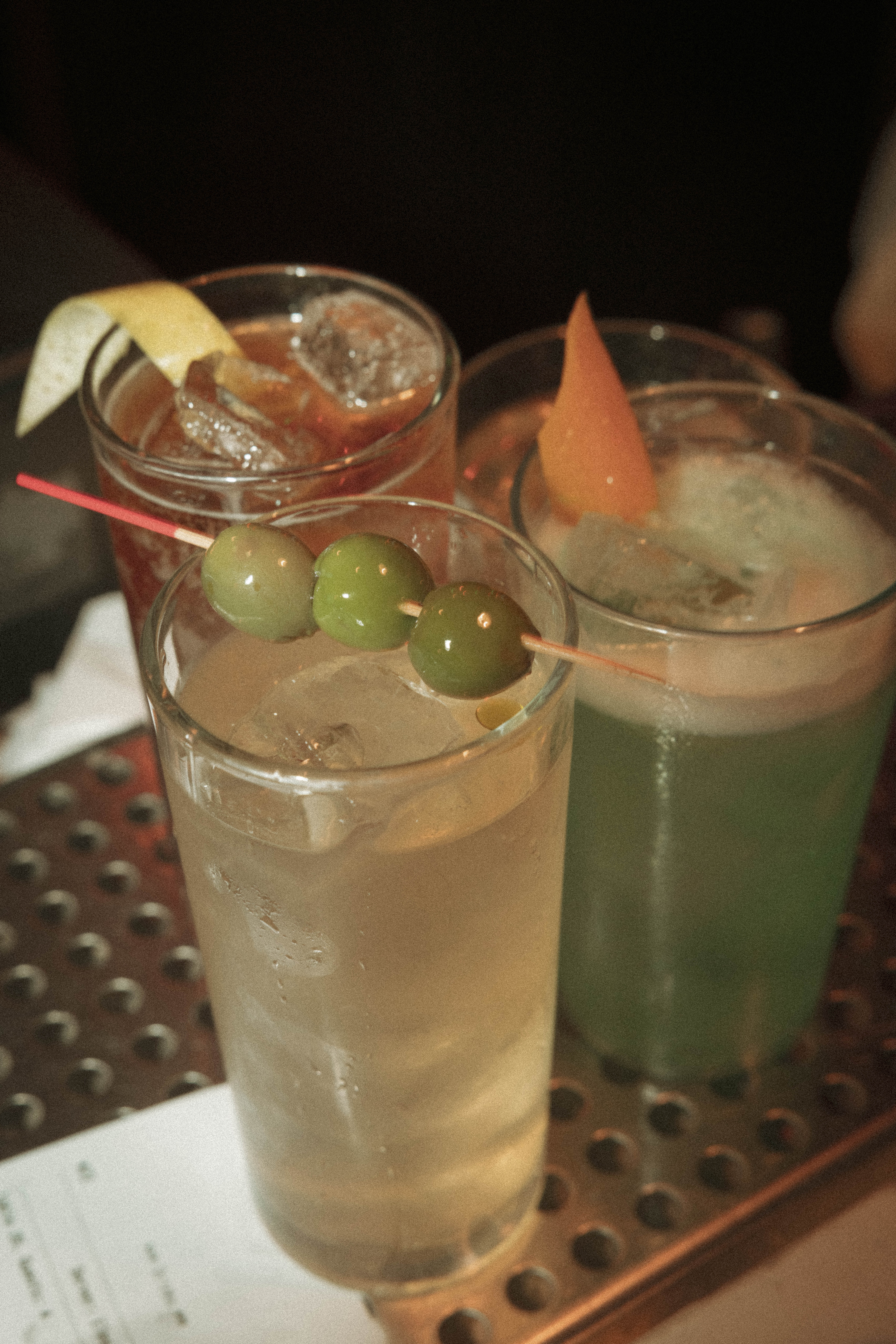 a group of drinks with olives on top