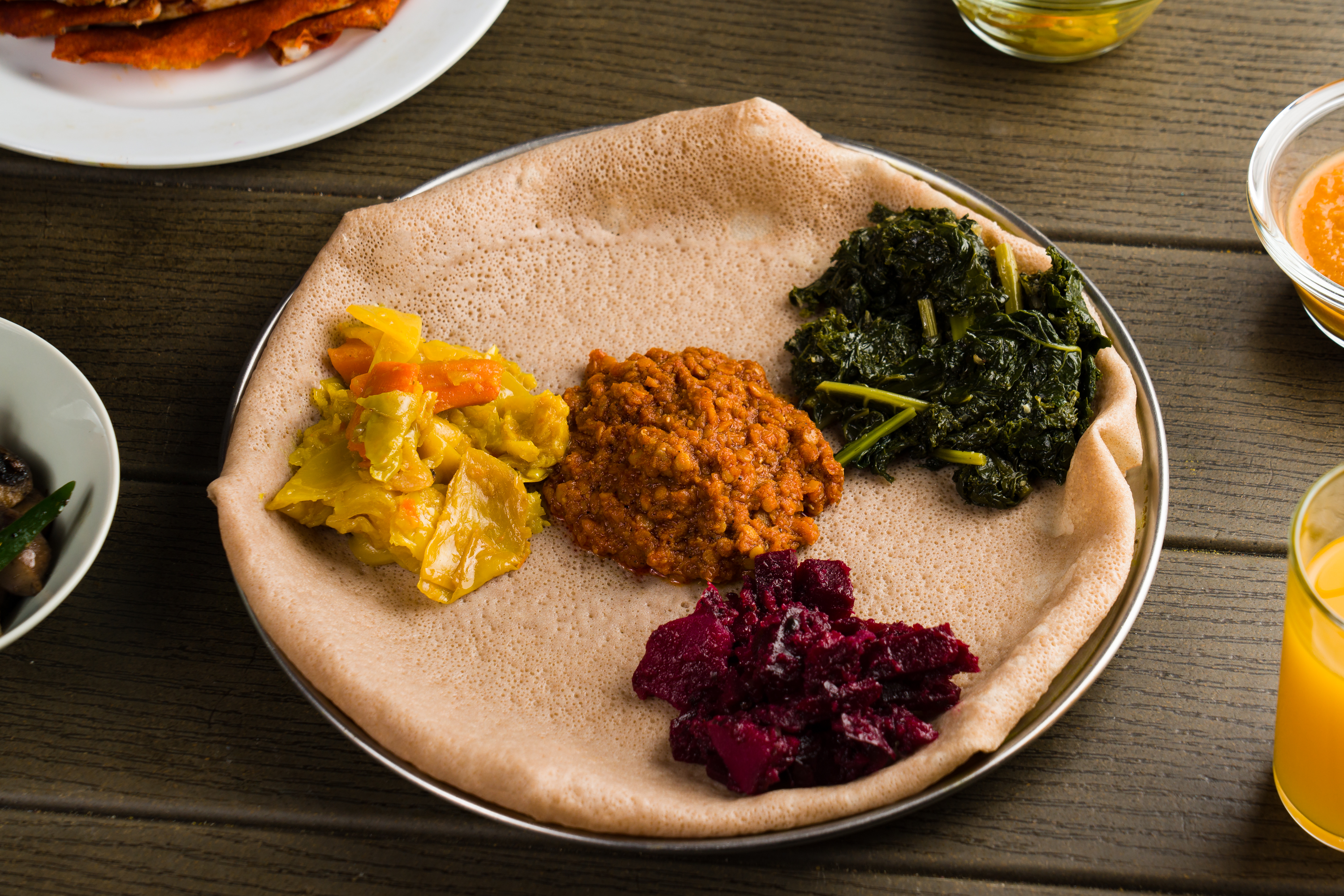 A sampler of our best vegan dishes — lentils, greens, cabbage, shiro, and more — served with gluten-free injera for a full, plant-based Ethiopian experience.