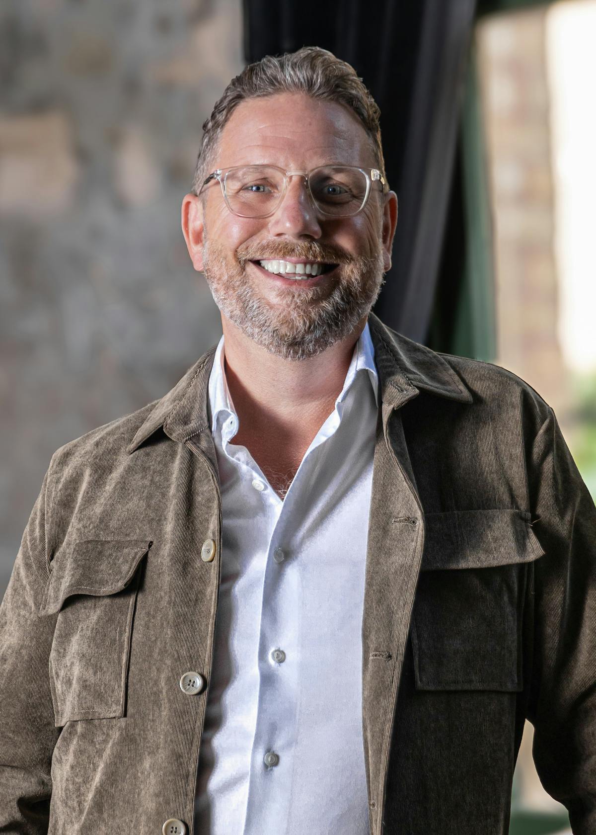 a man wearing glasses and smiling at the camera