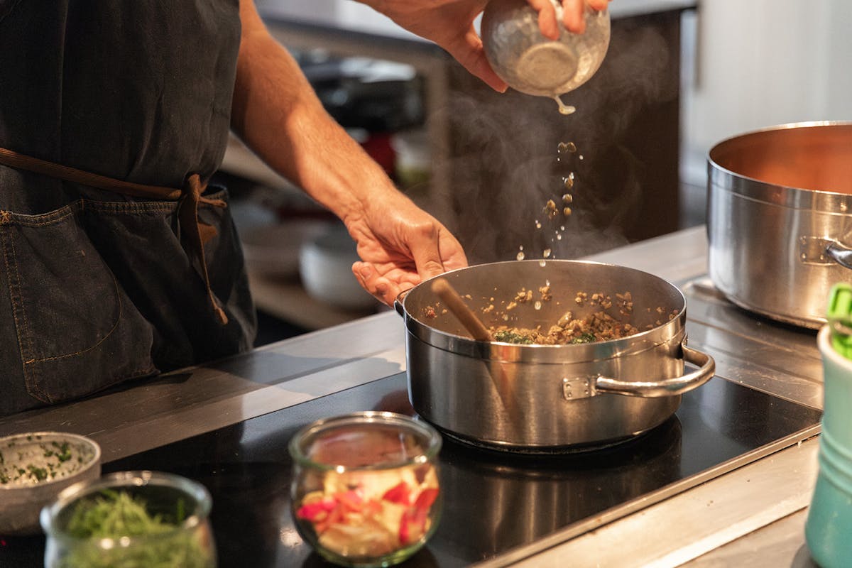 a person preparing food in a pan on a stove