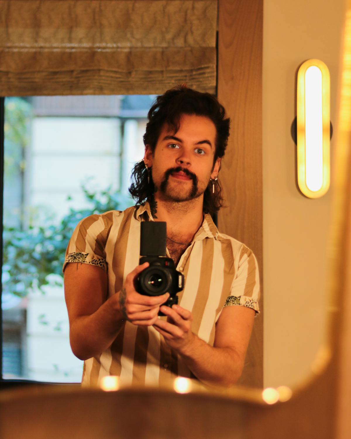a person holding a camera in front of a mirror posing for the camera