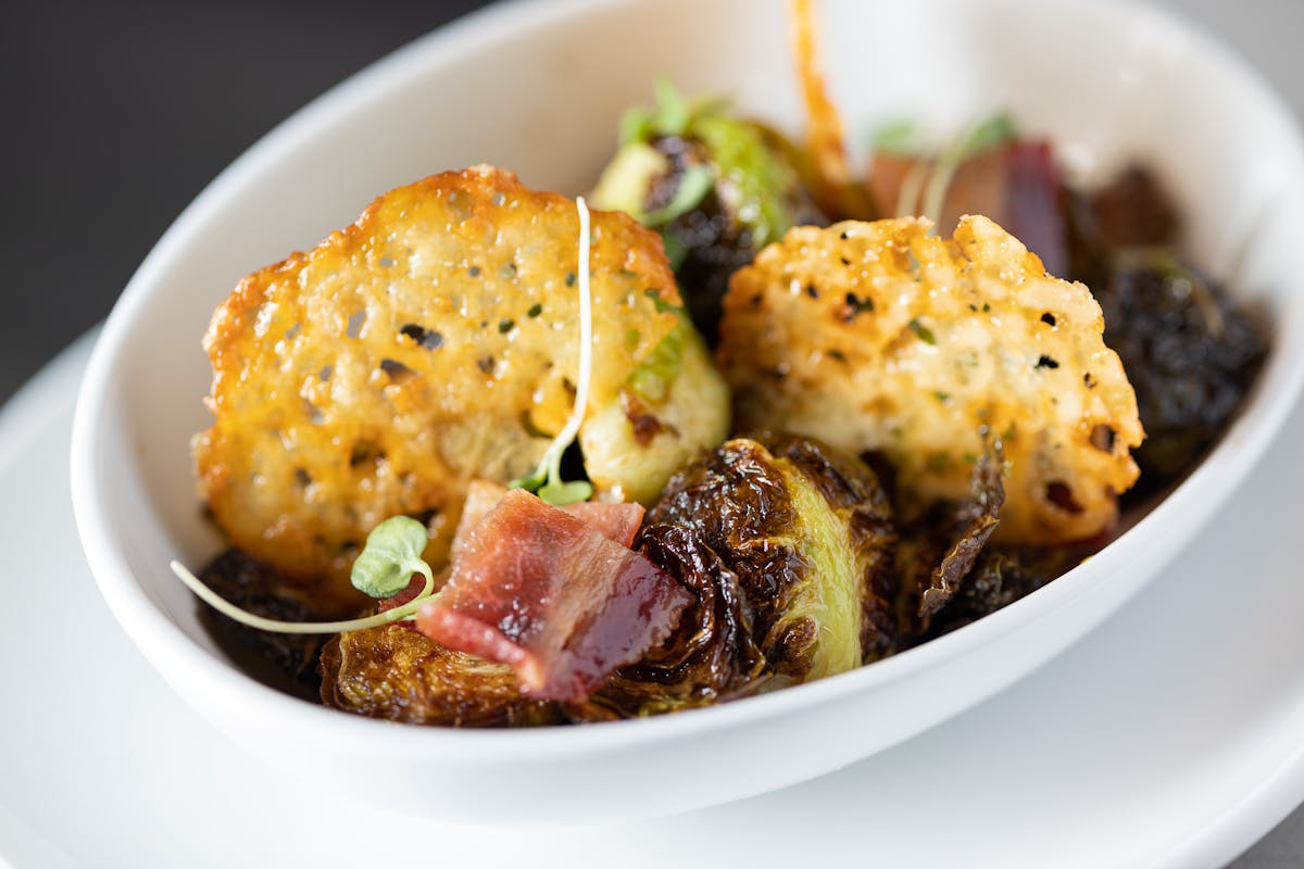 bowl with crispy Brussel sprouts, fried gouda tile, pine nuts and bacon