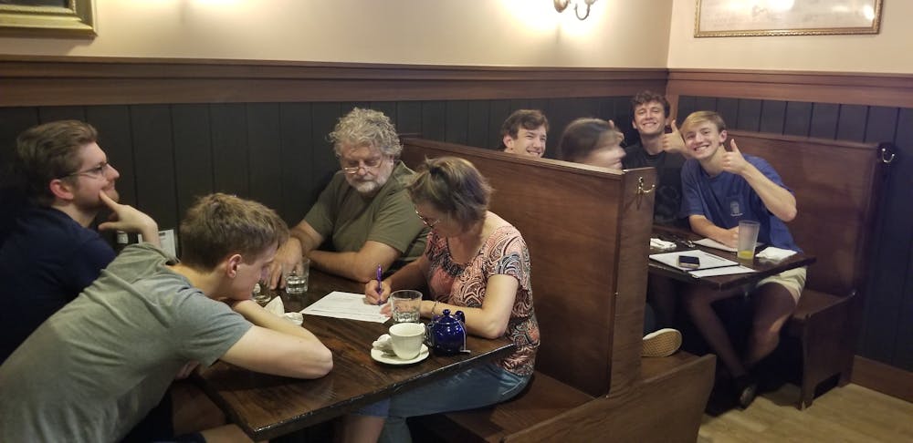a group of people sitting at a table with a cake
