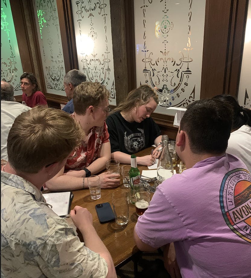 a group of people sitting at a table with a cake