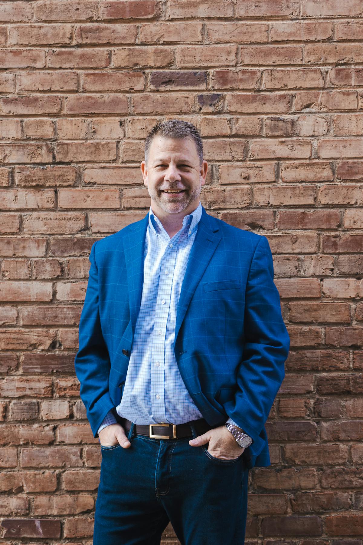 a man standing in front of a brick wall