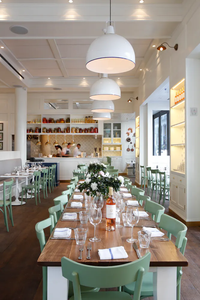 A close up of  a room with tables and people preparing food