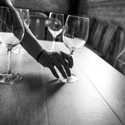 a person sitting at a table with wine glasses