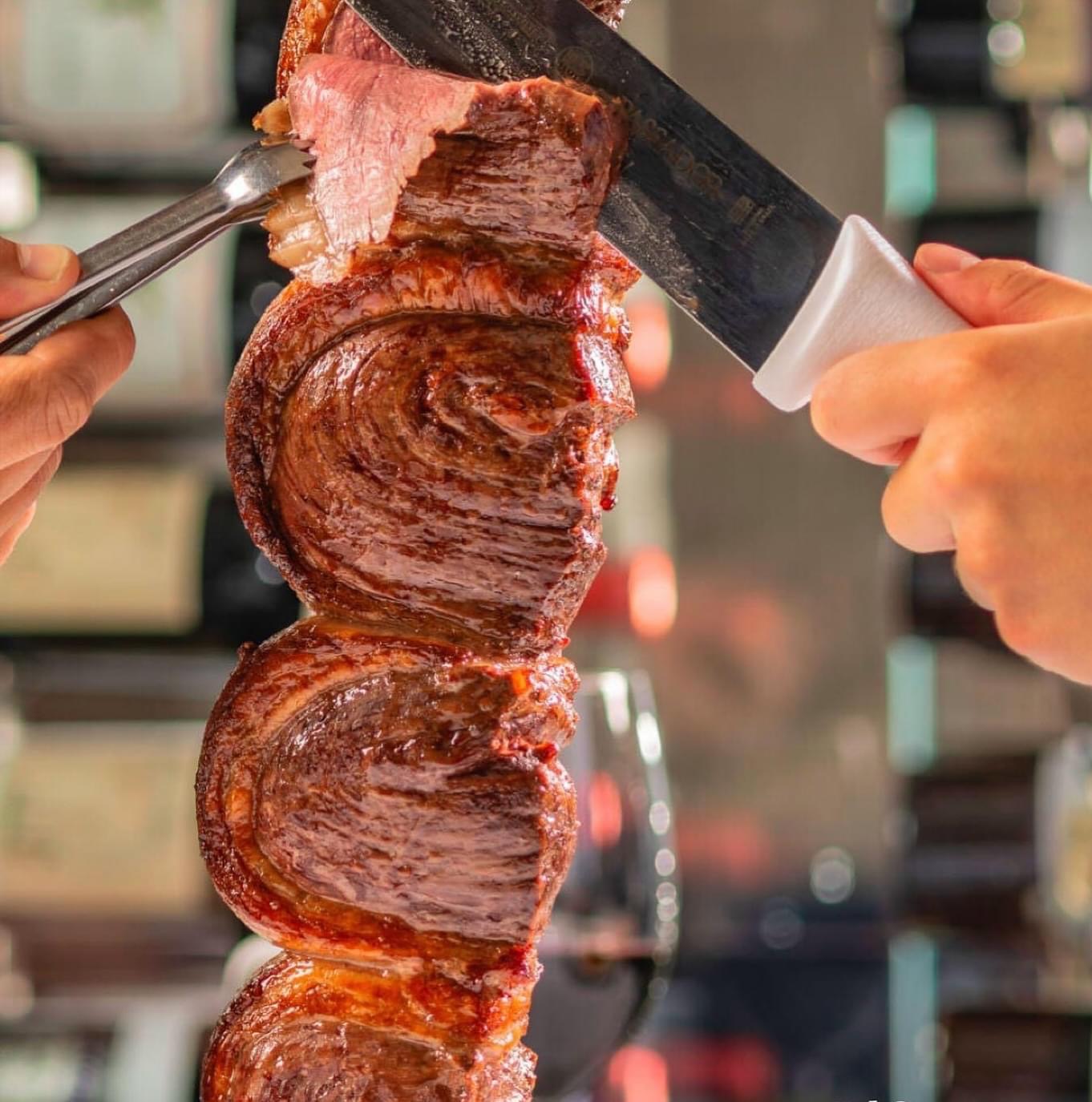 a hand holding a piece of meat on a cutting board