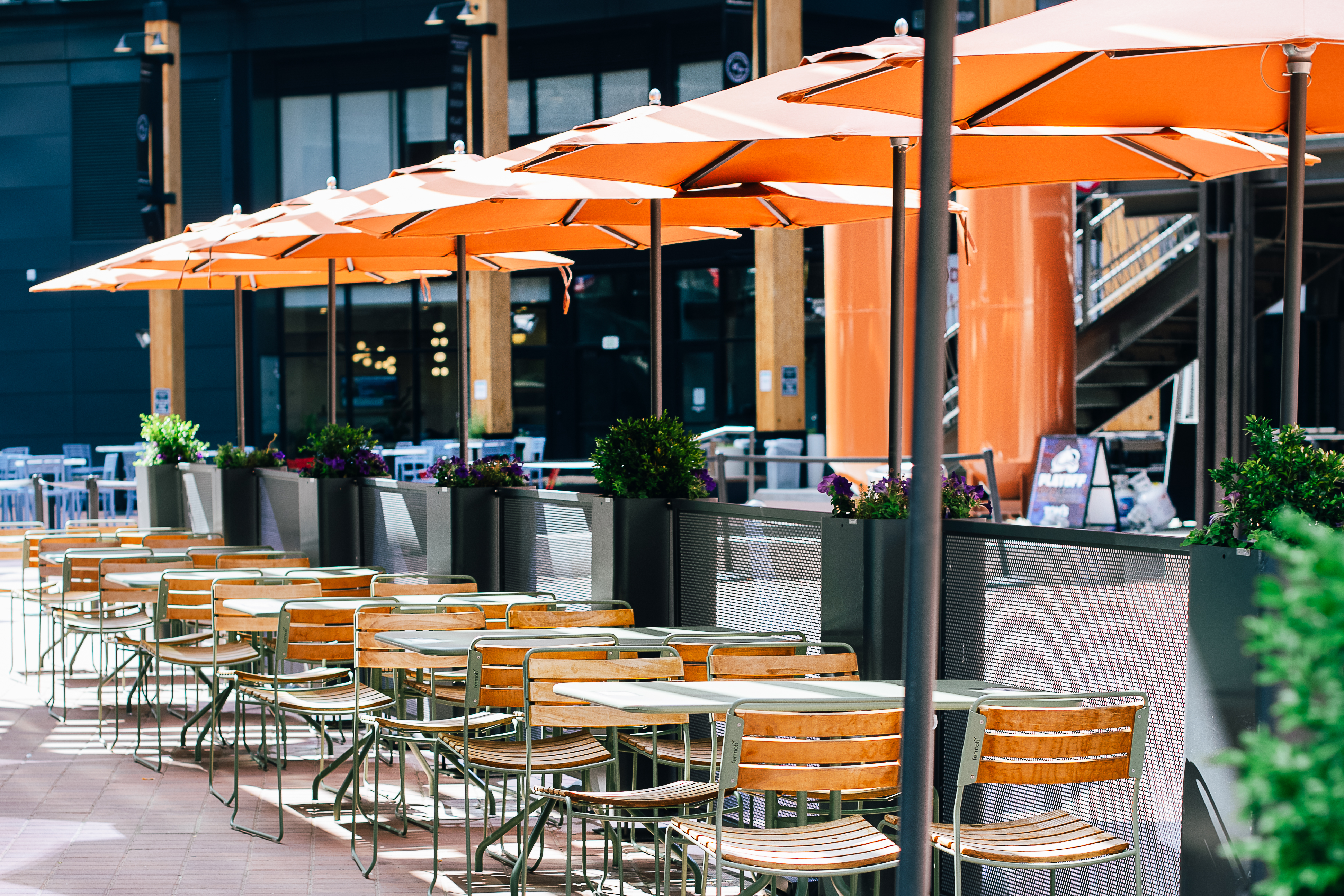 a group of people sitting at a table with an orange umbrella