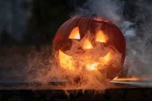 a carved pumpkin with a face and smoke