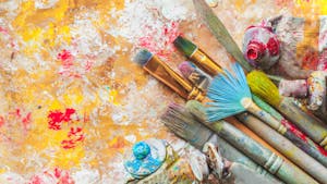 a group of paint brushes and paint tubes