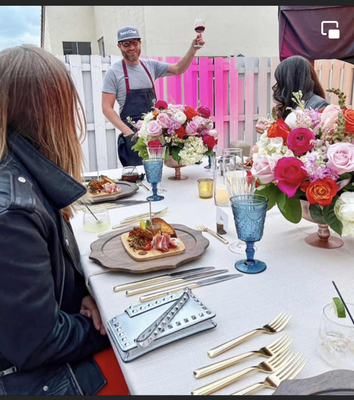 a group of people sitting at a table with a plate of food, cooking demo