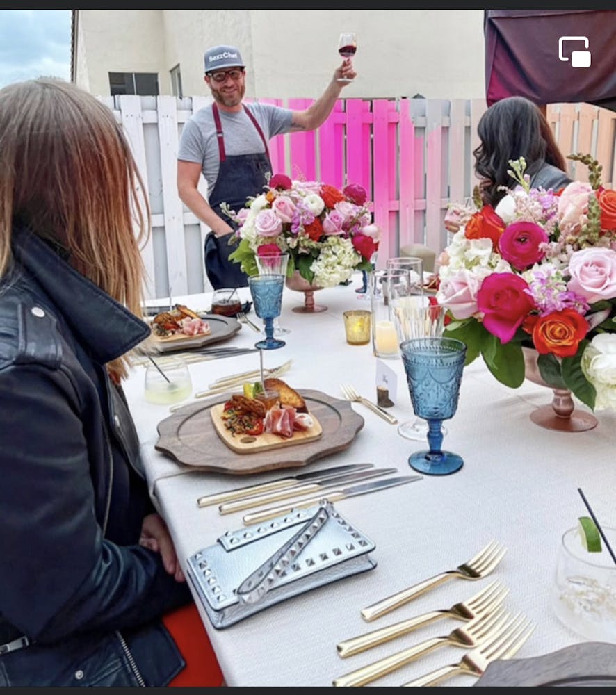 a group of people sitting at a table with a plate of food, cooking demo