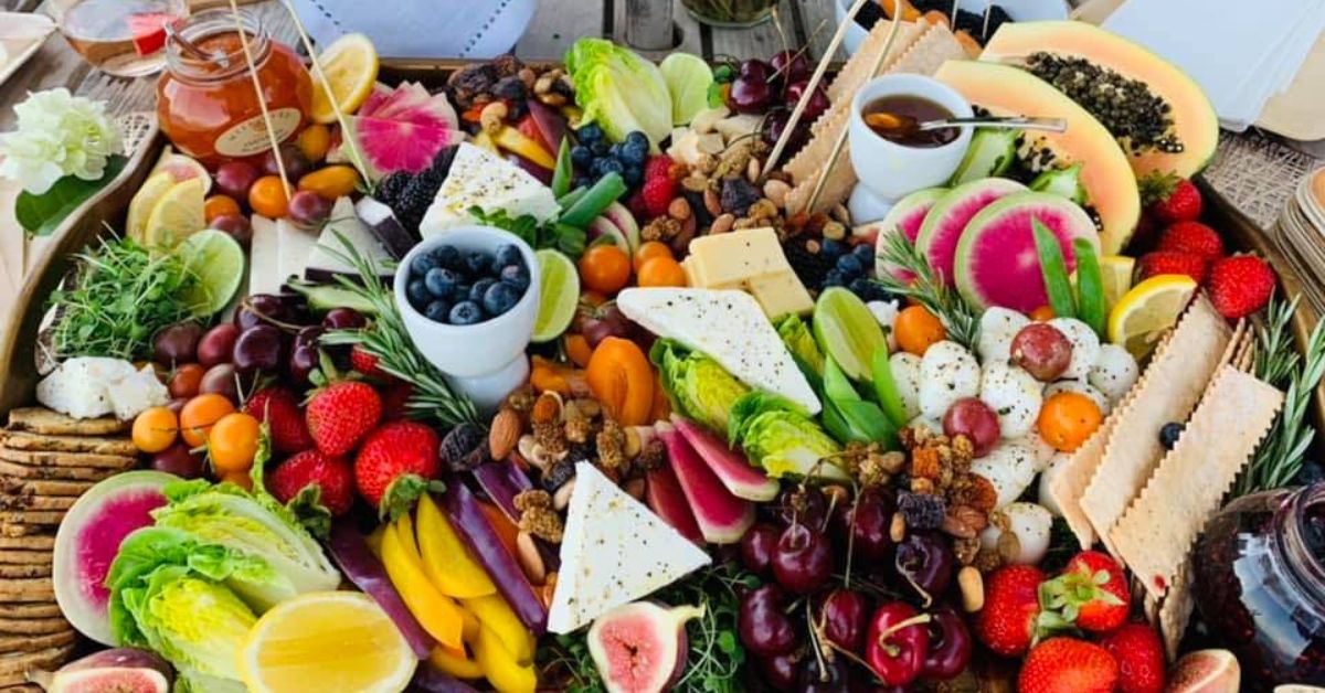 Colorful grazing table with fruit, vegetables, crackers, and gourmet selections for Delray Beach events