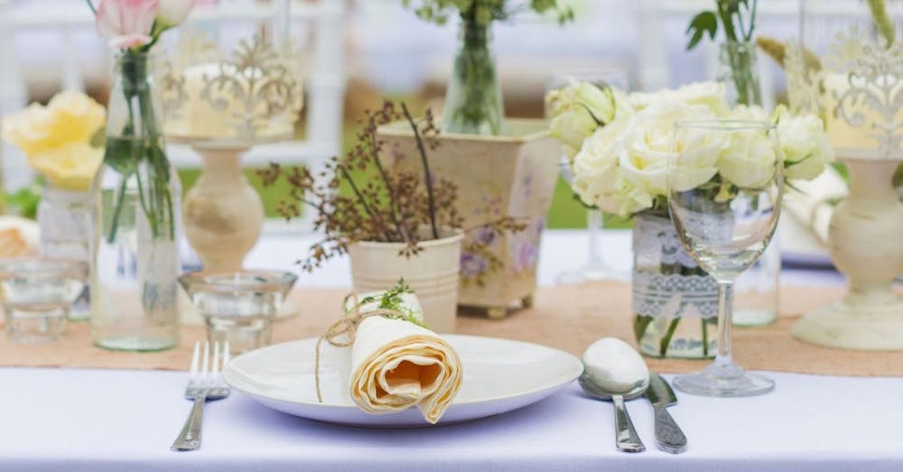 Elegant bespoke catering table setup with flowers, candles, and fine dining arrangement