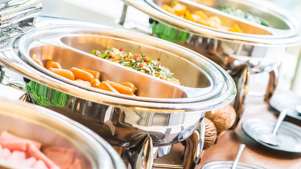 Buffet-style catering setup featuring gourmet dishes in heated containers by Potions in Motion in Boca Raton