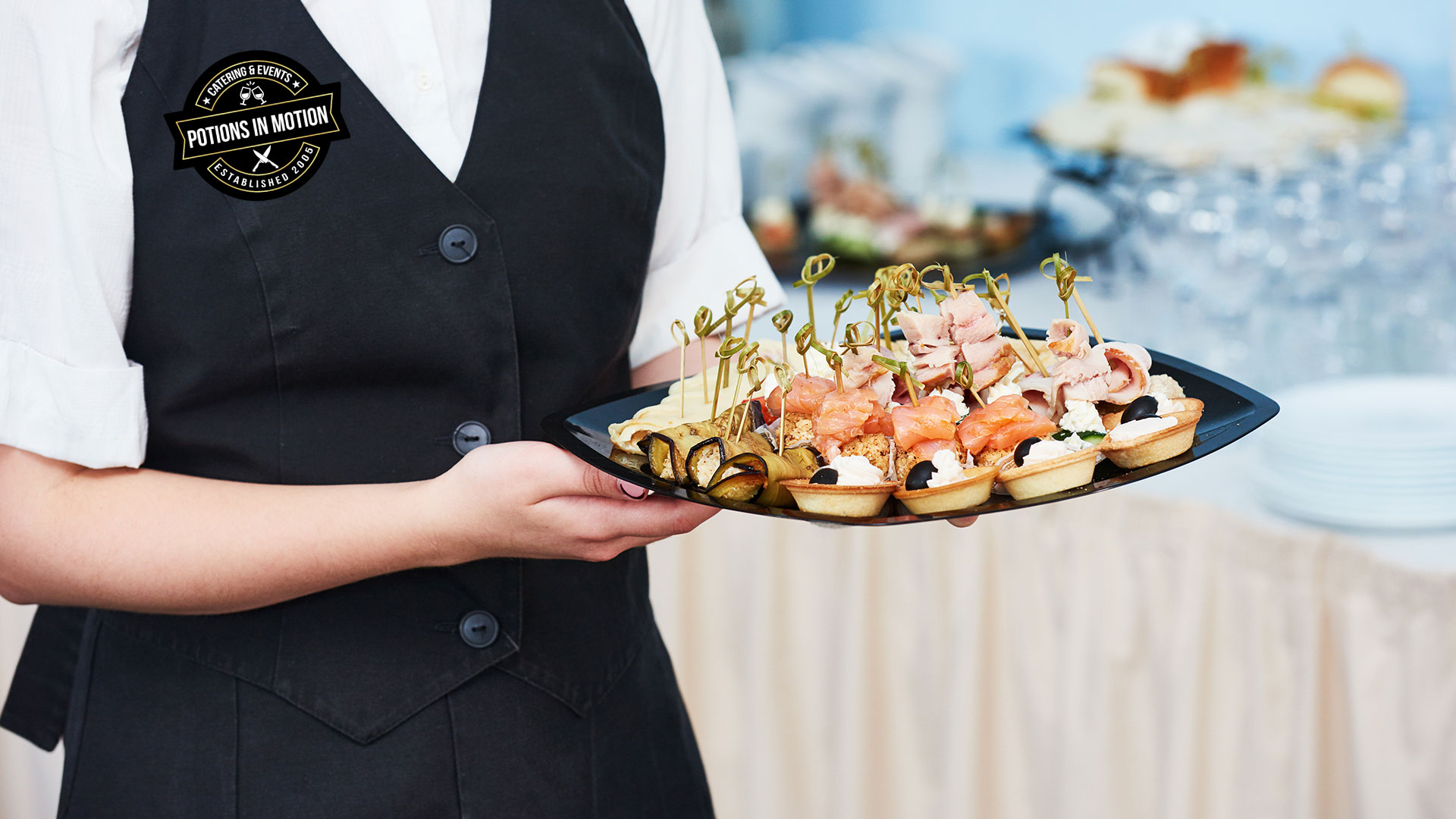 Server holding tray of assorted hors d’oeuvres at Potions In Motion cocktail party catering event Title: Professional Service at Cocktail Party Catering Events