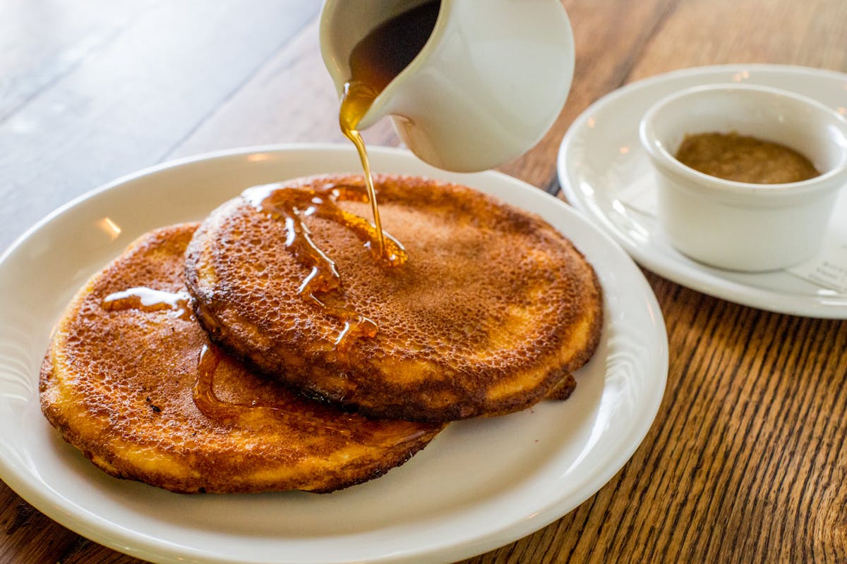 Our ricotta pancakes being drizzled with maple syrup