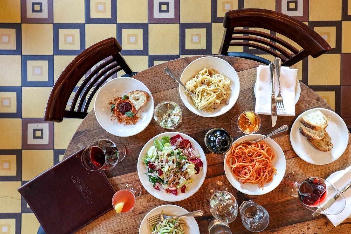 a full spread of food at Maialino - pastas, salad, sides, and wine