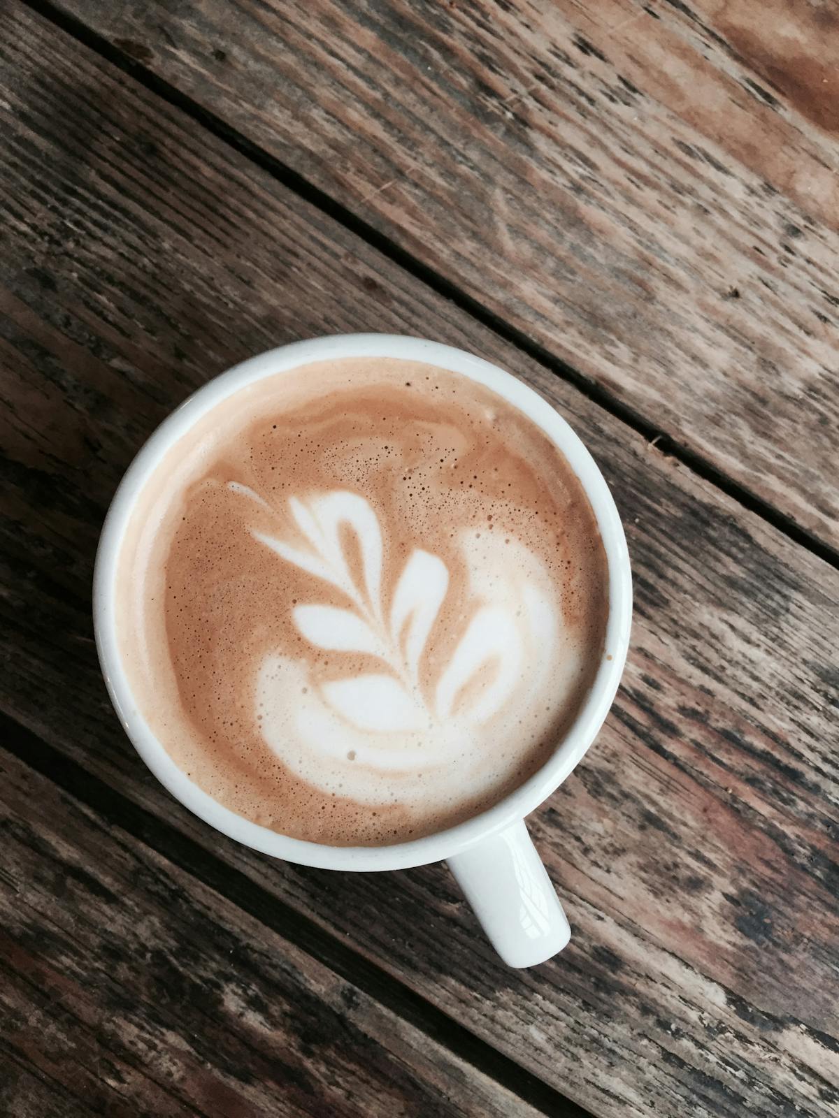 a cup of coffee sitting on top of a wooden table