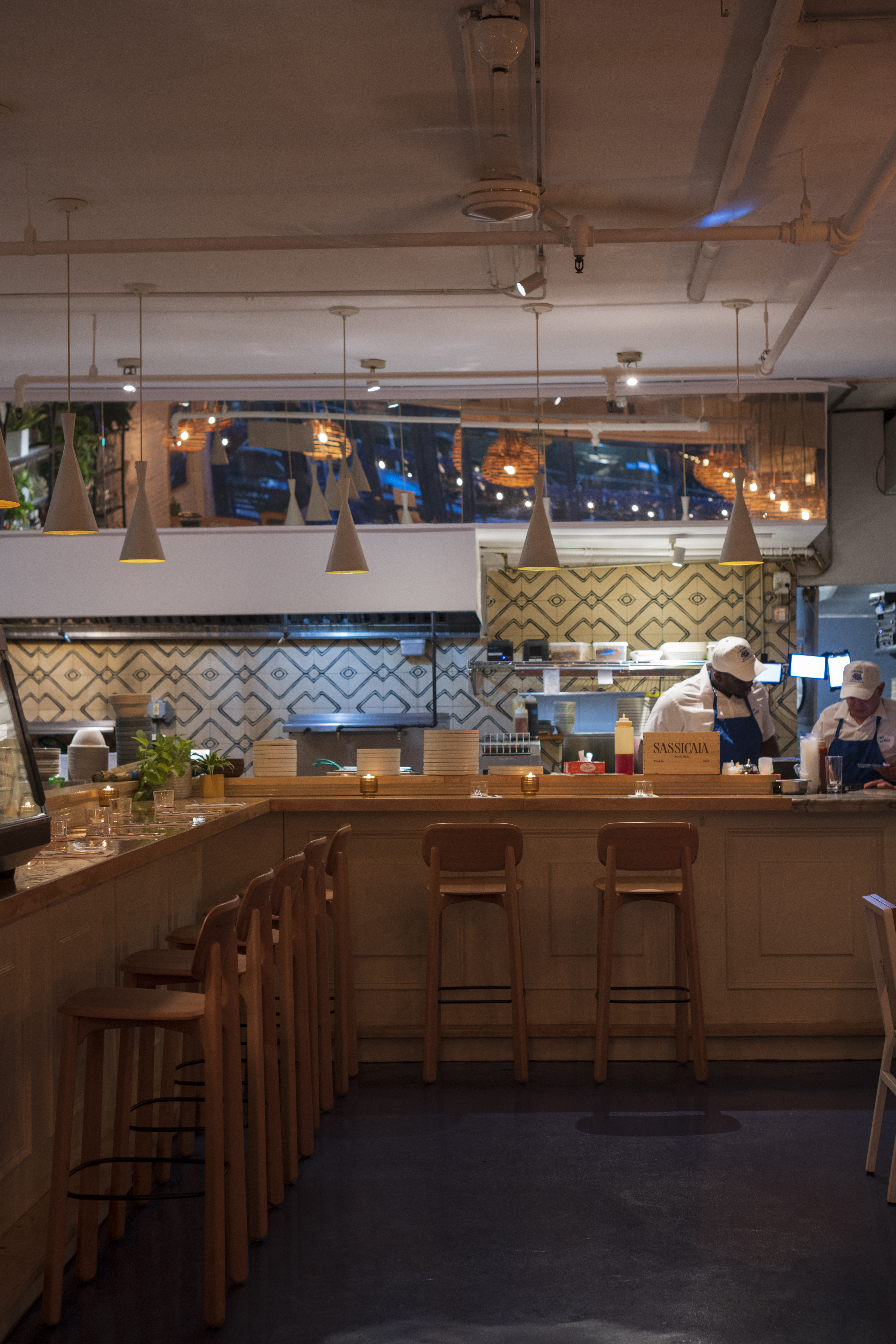 a man in a white hat behind a counter in a restaurant