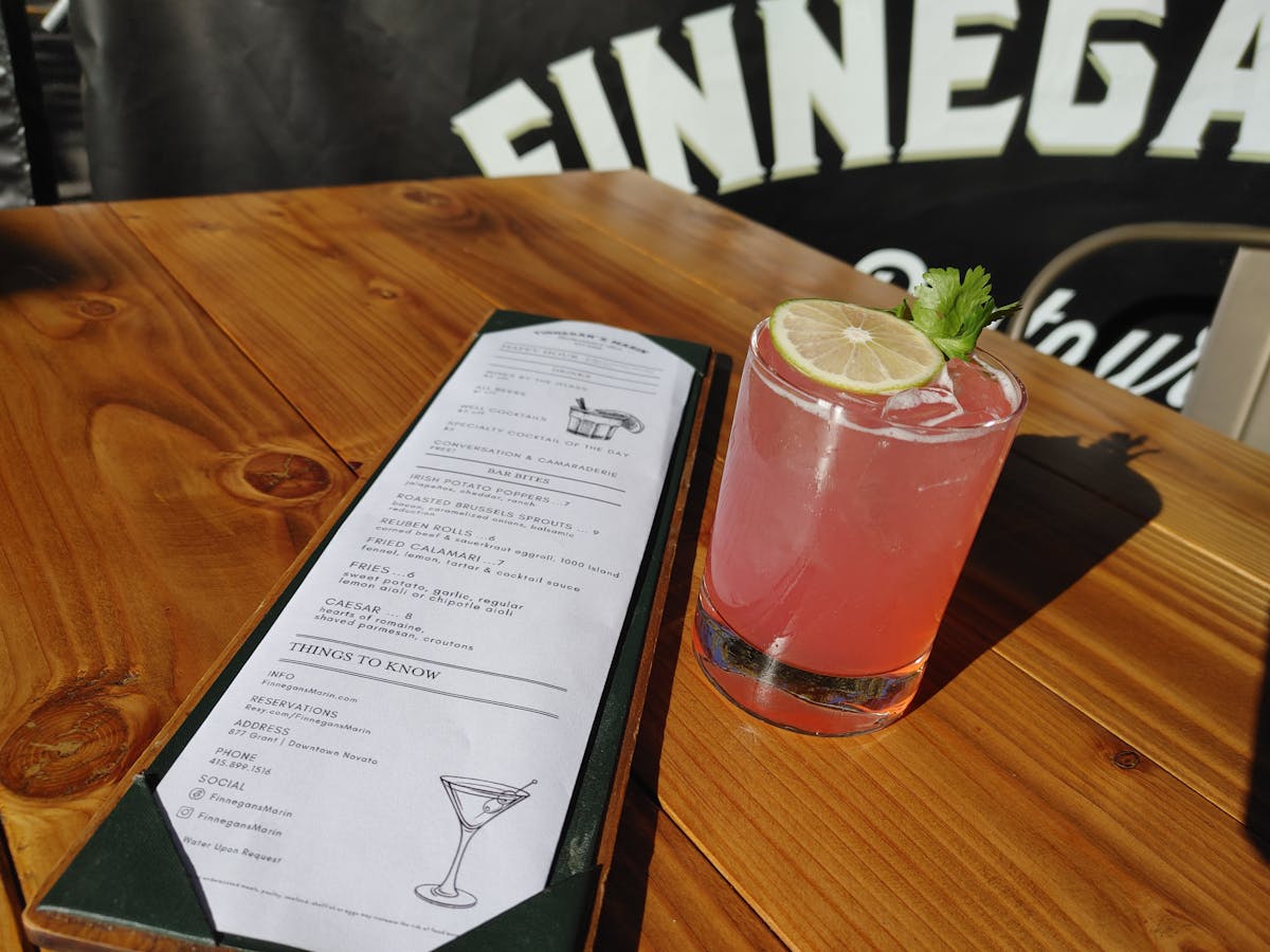 A craft cocktail and happy hour menu on a table