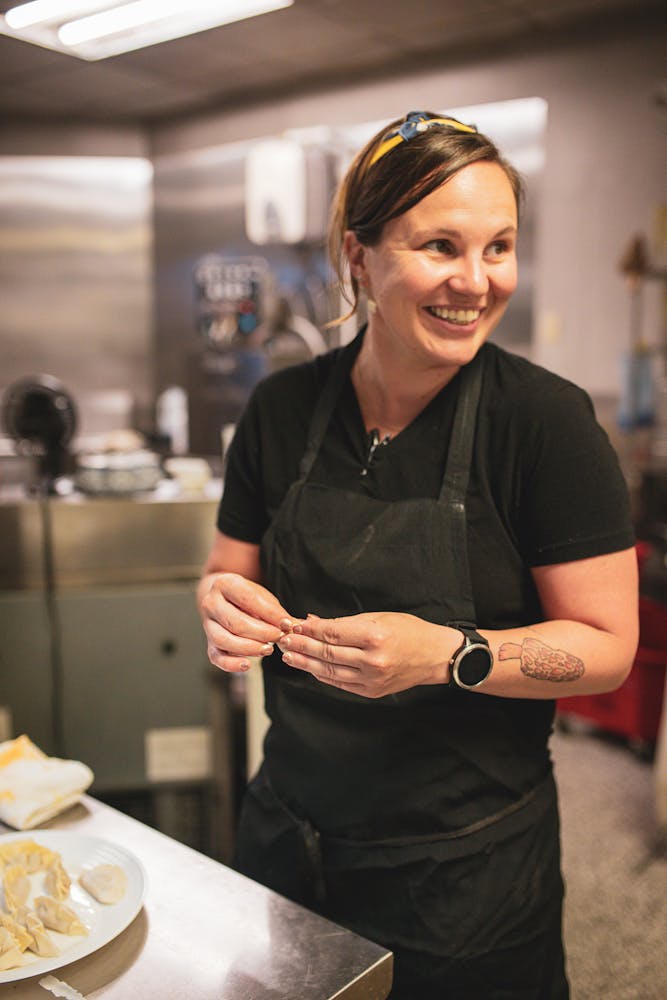 a woman standing in a kitchen preparing food