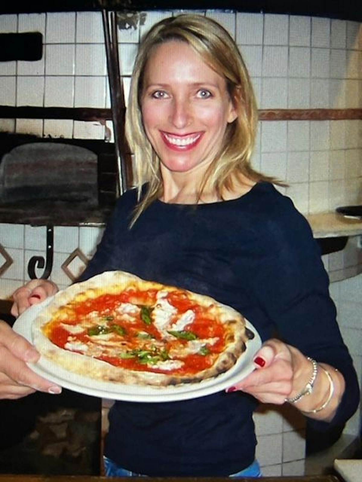 a woman holding a plate of pizza