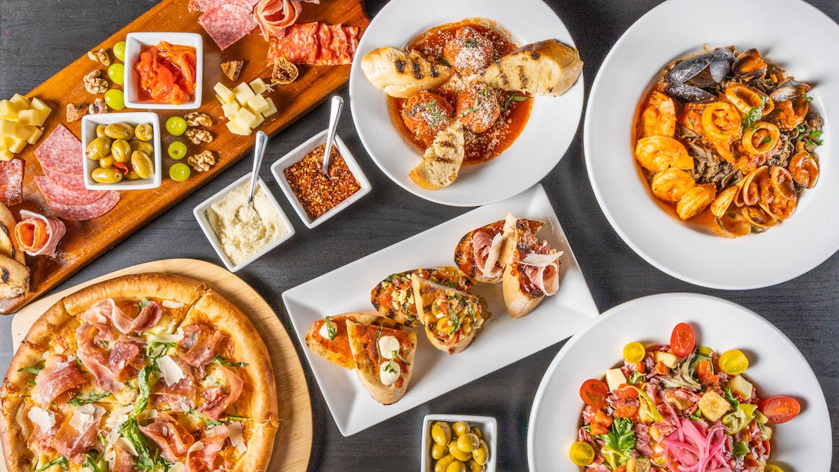 a table filled with pizza, charcuterie boards, meatballs,