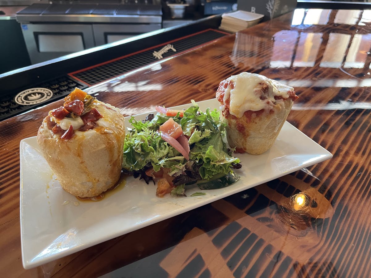 two hollowed breads filled with italian food and salad