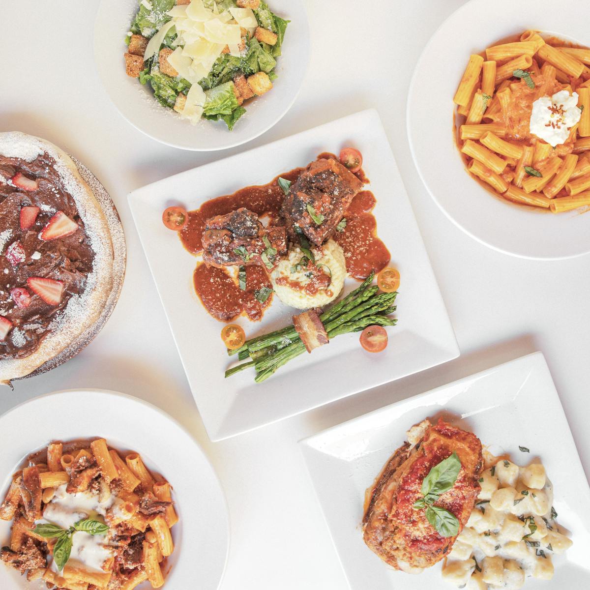 plates of italian food on white table