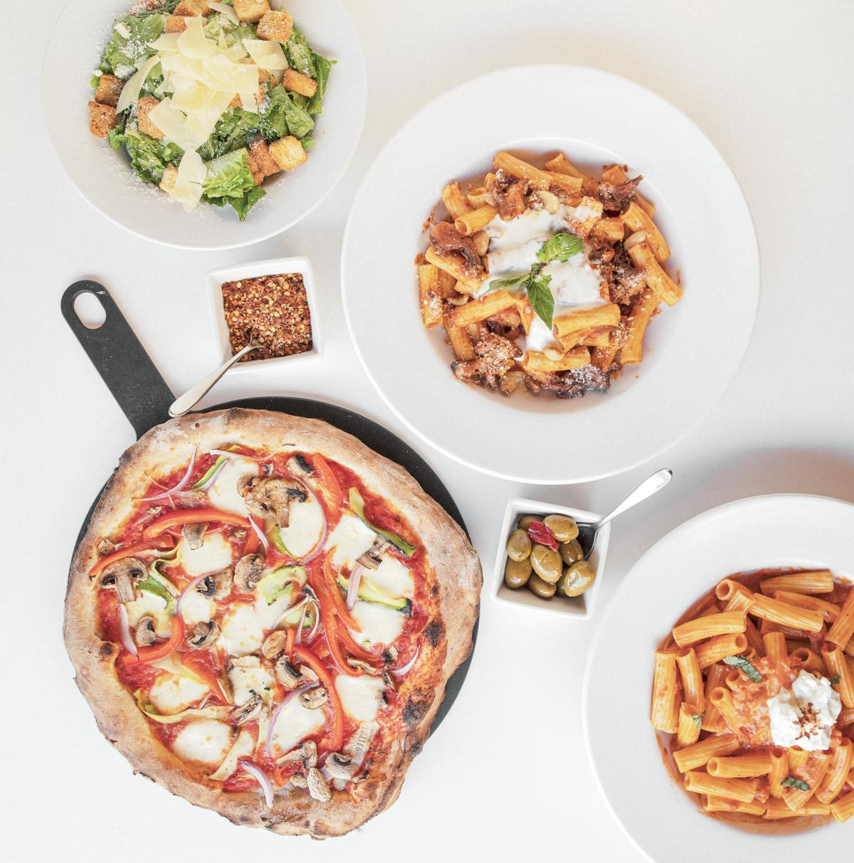 a table with salad, pizza, pasta