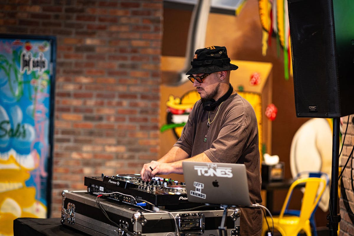 DJ performing live at Fat Sal’s Las Vegas location during an in-store event, with colorful street art and restaurant decor in the background