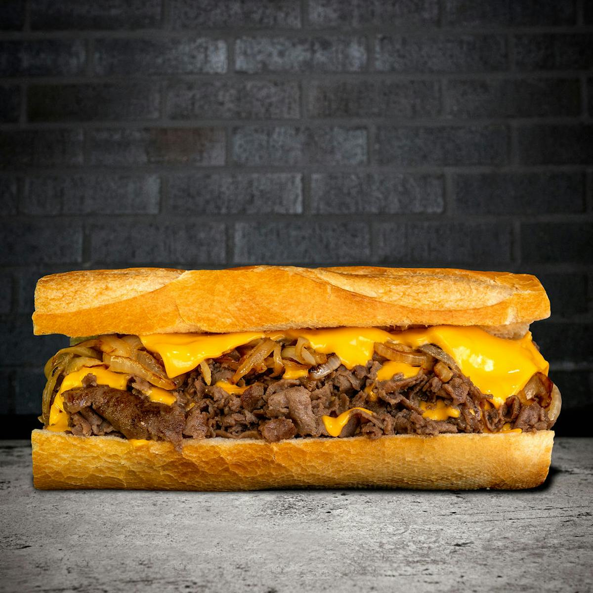 Close-up of a Philly cheesesteak sandwich with thinly sliced ribeye, melted American cheese, and grilled onions on a warm hero roll.