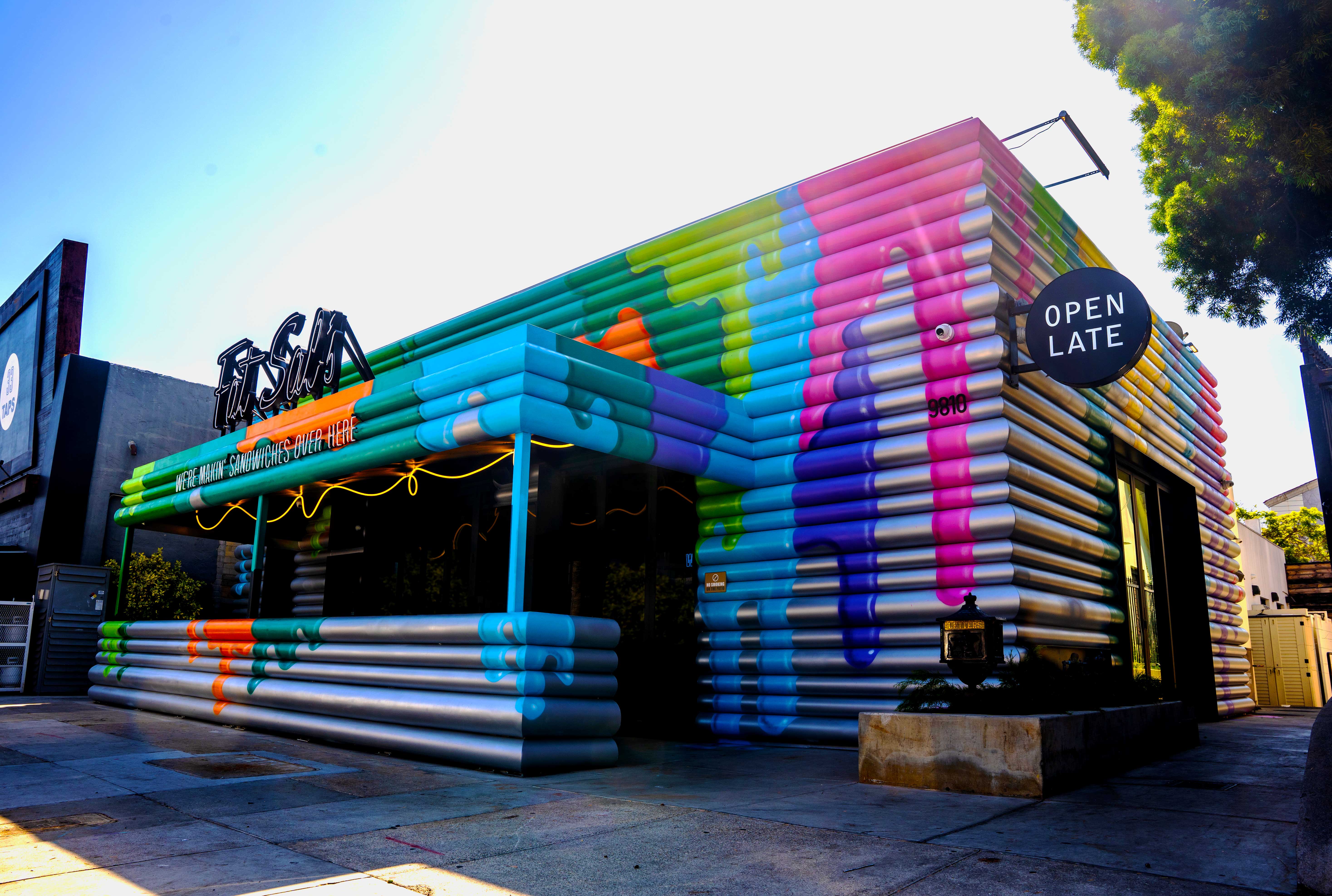 Exterior of Fat Sal’s Culver City location, featuring a colorful, striped mural design with dripping paint effects, bold Fat Sal’s signage, and a circular “Open Late” sign.