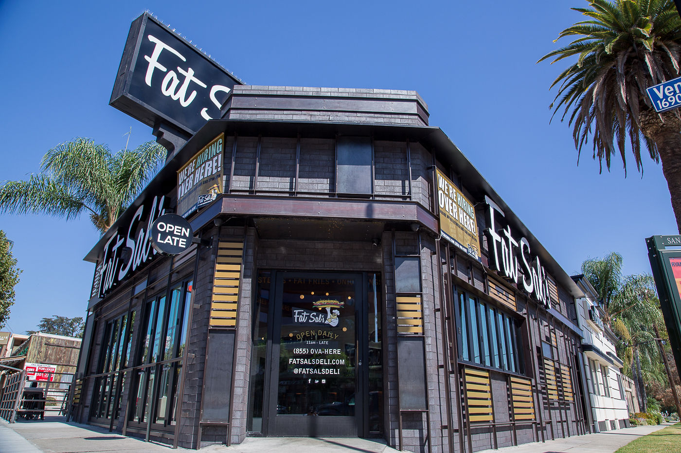 Fat Sal’s Encino location on Ventura Blvd with dark wood paneling, bold signage, palm trees, and a bright blue sky overhead.
