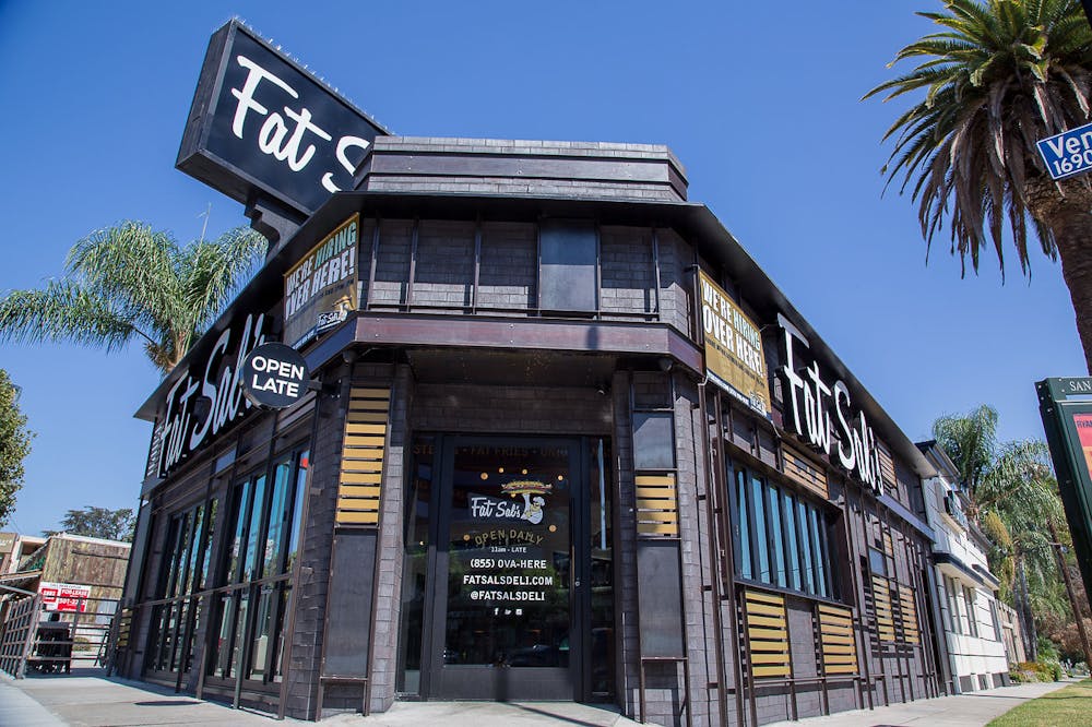 Fat Sal’s Encino location on Ventura Blvd with dark wood paneling, bold signage, palm trees, and a bright blue sky overhead.