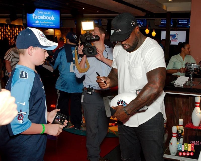 Delanie Walker signing a custom ball for a fan. a group of people standing in a room