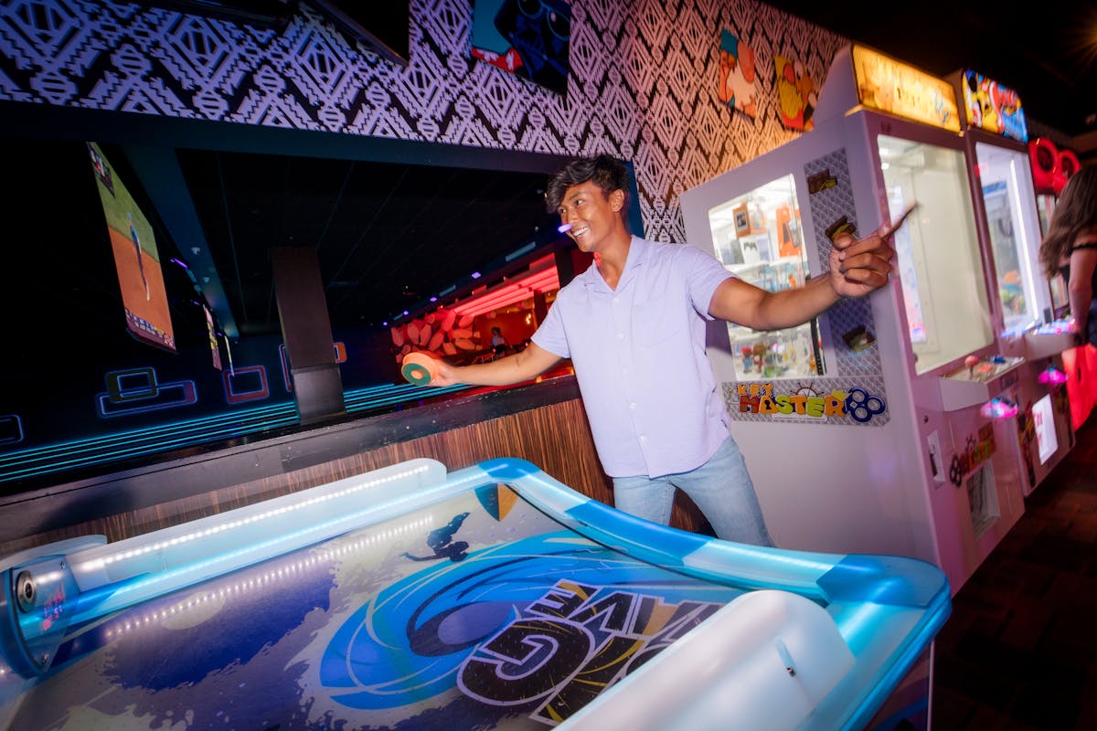 A man playing air hockey in an arcade