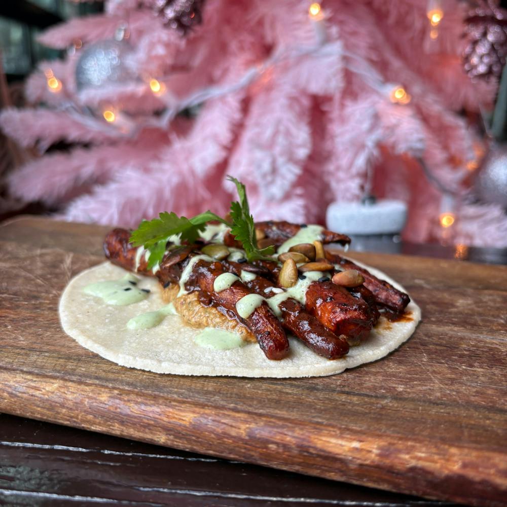 Carrot Mole Taco at Dos Santos with roasted carrots, mole sauce, sikil pak, cilantro crema, sesame seeds, and pepitas.