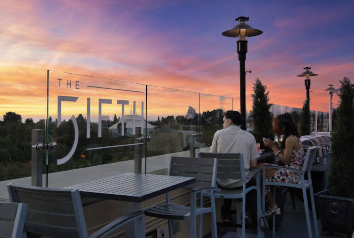 a group of people sitting at a table with a sunset in the background