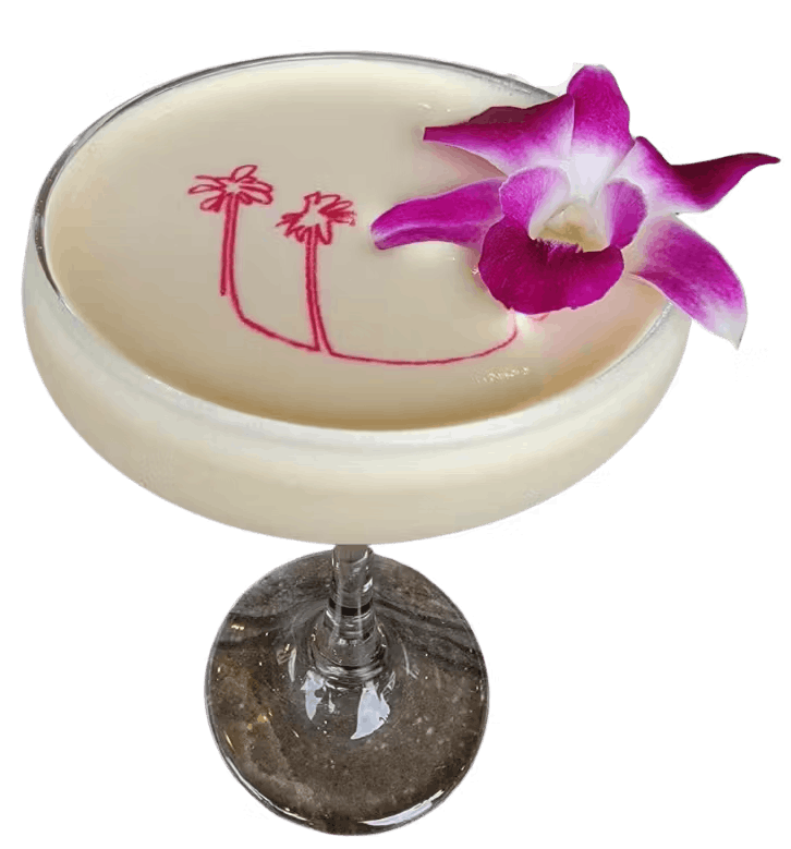 Creamy coconut rum cocktail with palm tree art displayed and a purple flower sitting on top