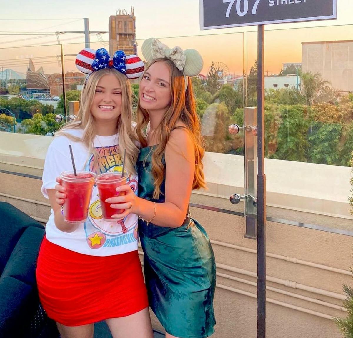 two women holding a cocktail posing for the camera