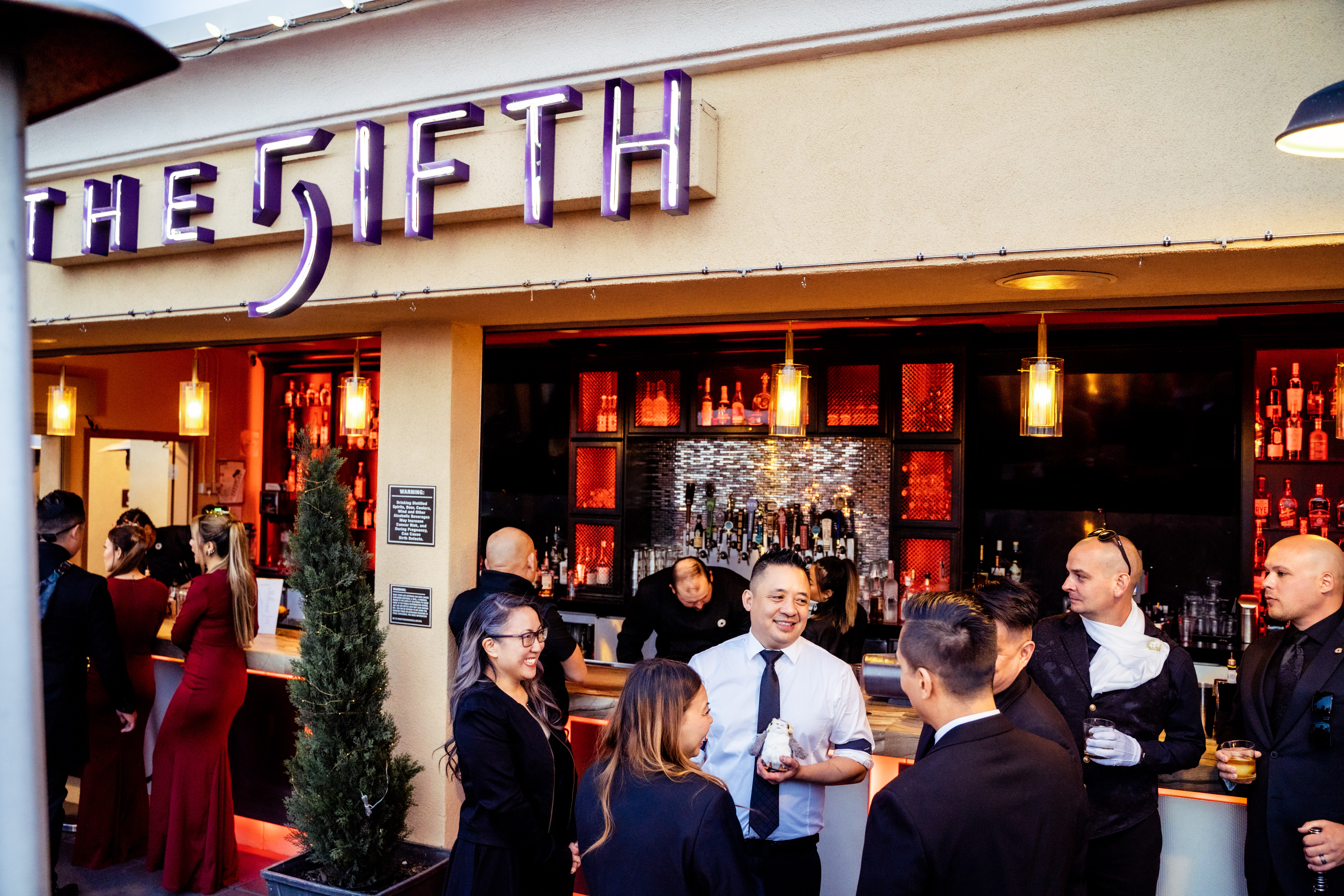 Guests enjoying a private event at The FIFTH Rooftop Restaurant & Bar in Anaheim, featuring an open-air bar, handcrafted cocktails, and event space near Disneyland® Resort.