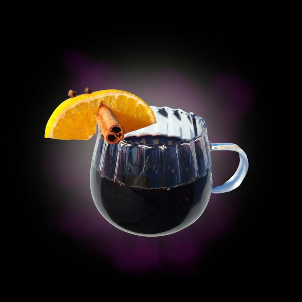 a small tea glass with spiced red wine and cinnamon, clove and orange garnish