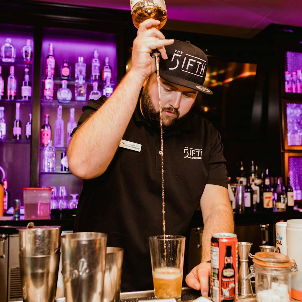 a man holding a glass of beer on a table