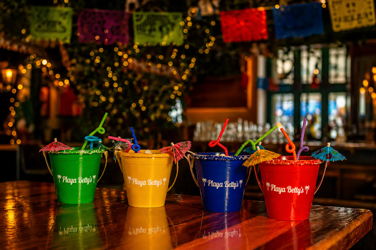 a group of colorful buckets with straws on a table
