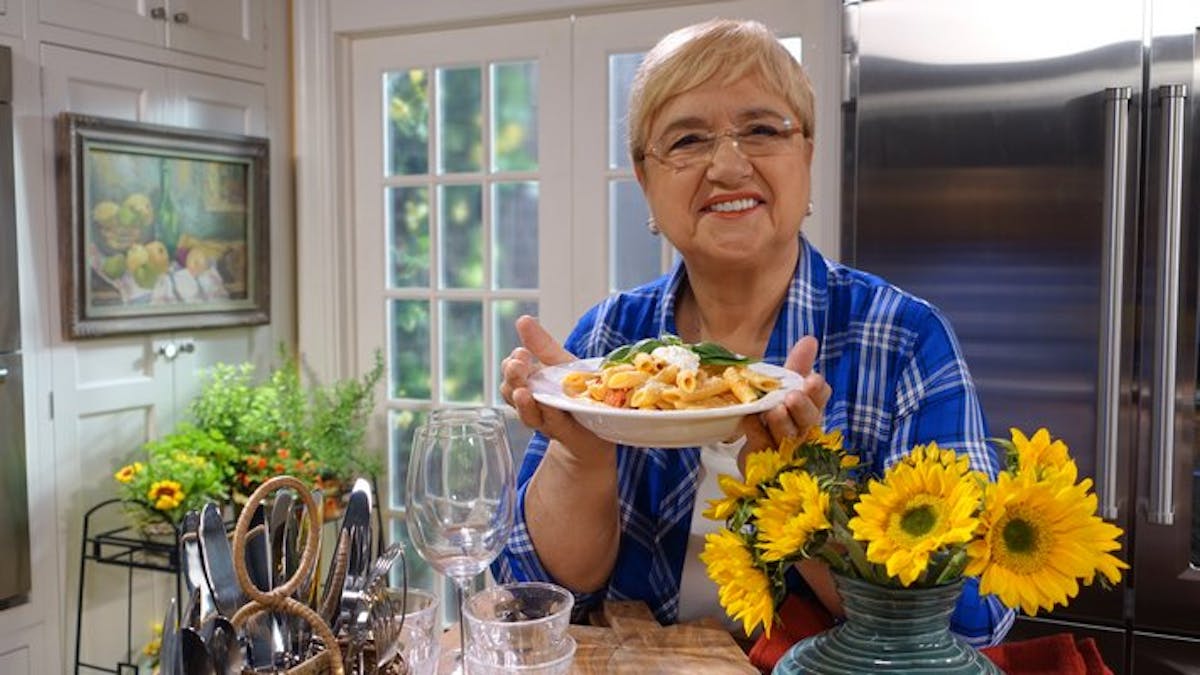 Lidia Bastianich sitting at a table with a vase of flowers