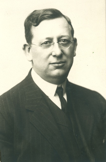 a man wearing a suit and tie smiling at the camera